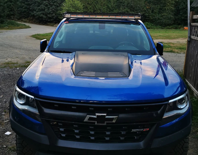 Front view of blue Chevy ZR2 truck with hood scoop and LED light bar, parked outdoors.