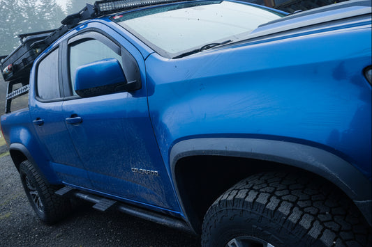 Blue ZR2 with roof rack and lights in a foggy forest setting